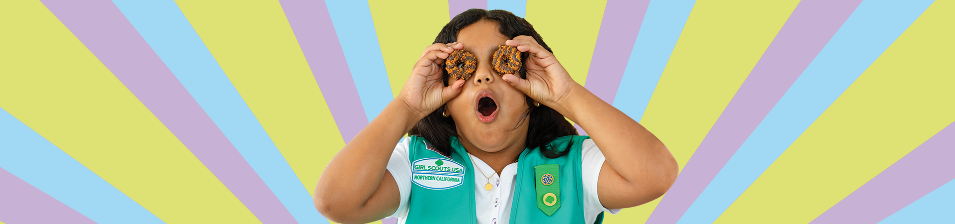  A Girl Scout holding Girl Scout cookies over eyes 