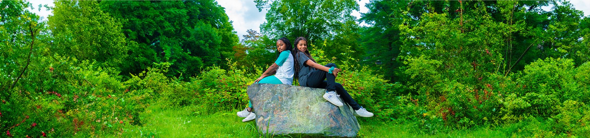 two Junior Girl Scouts sitting on a boulder 