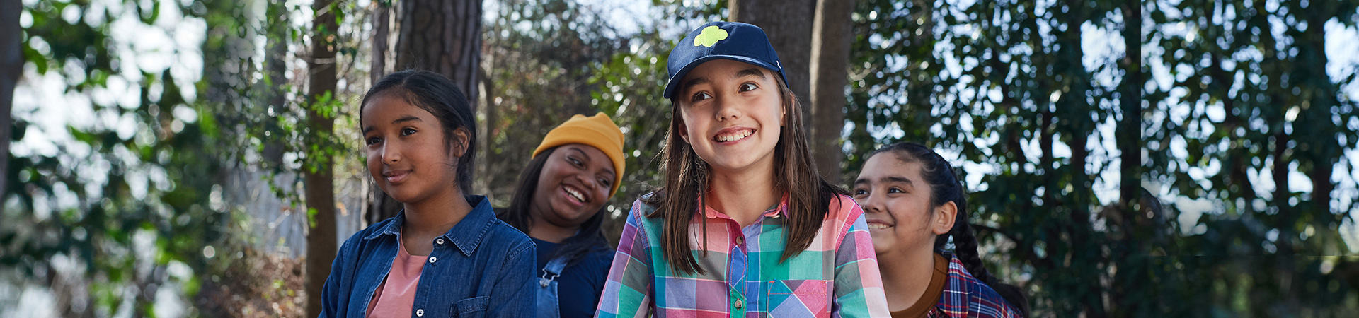  three young girl scouts with their arms wrapped around one another and smiling at the camera 