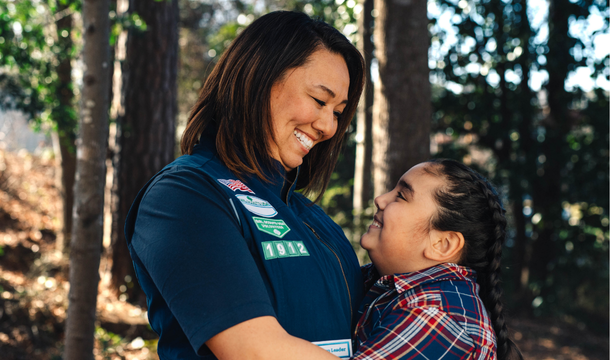 A Girl Scout adult and youth member hugging.